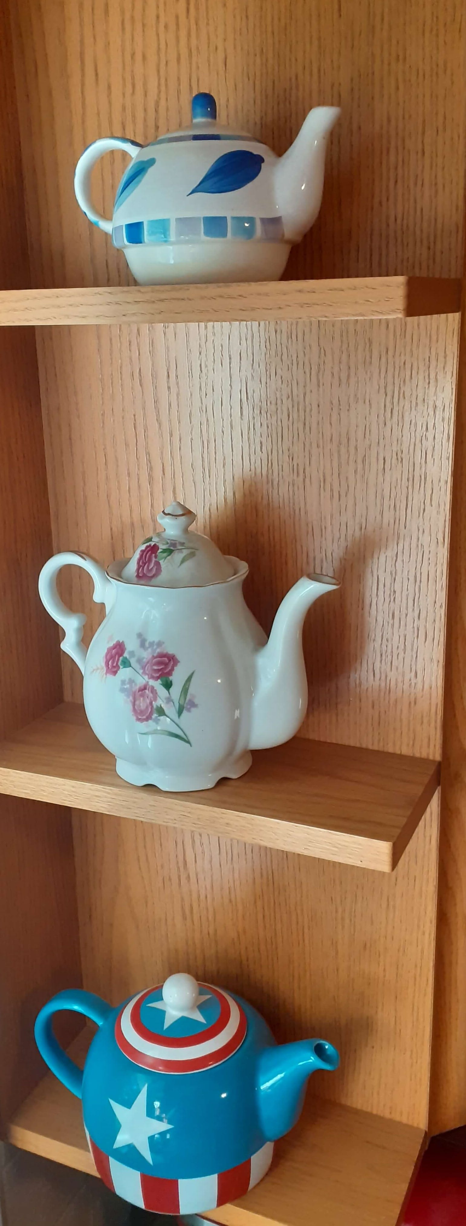 three tea pots on shelves