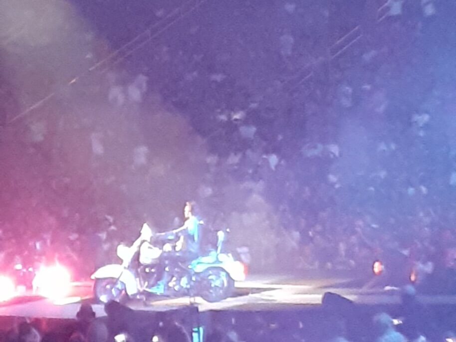 Adam Lambert singing on a motorcycle.